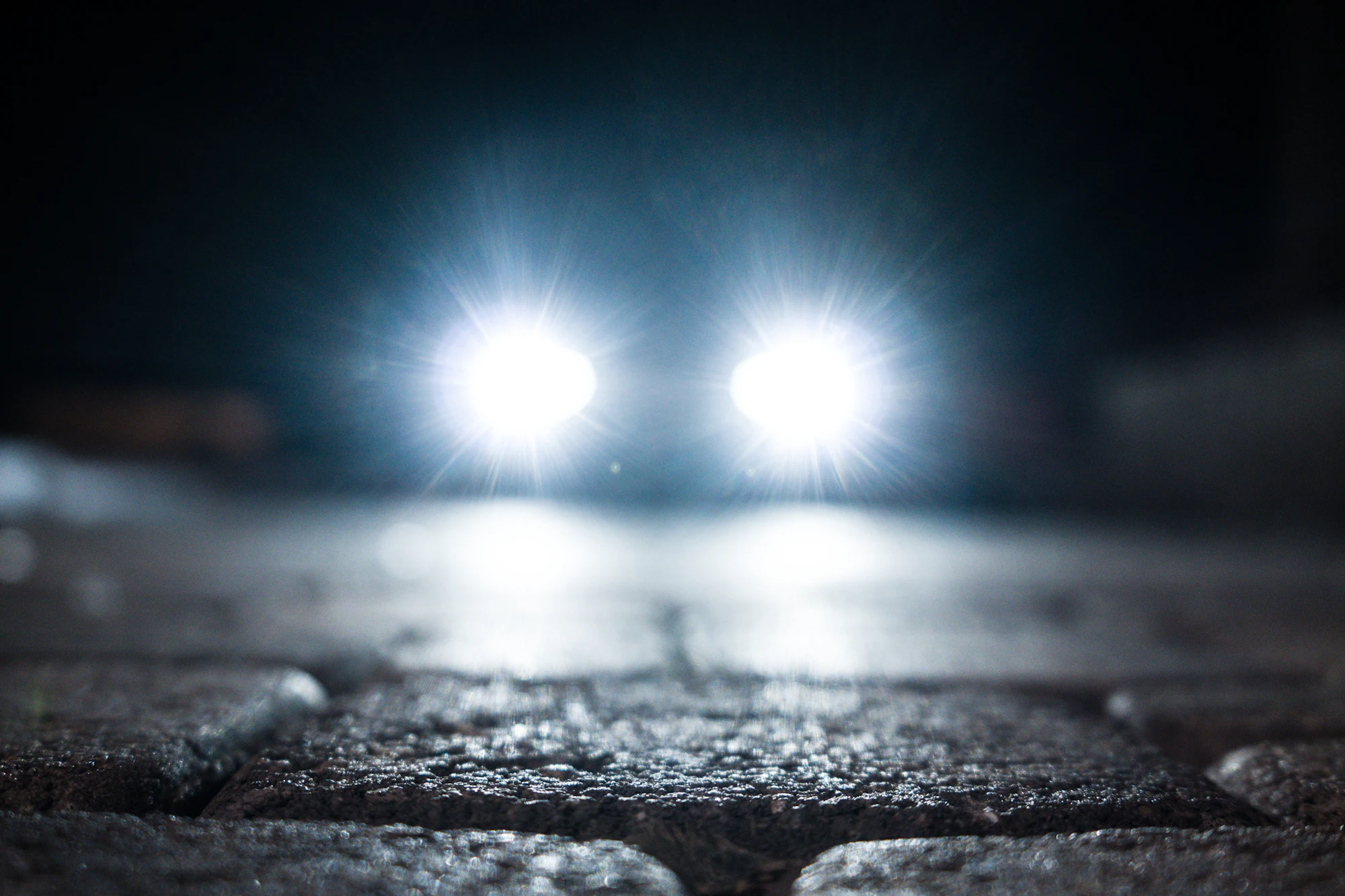 Car headlights glowing on a dark street