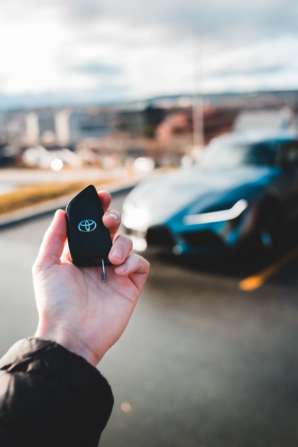 Toyota key held up in front of a car